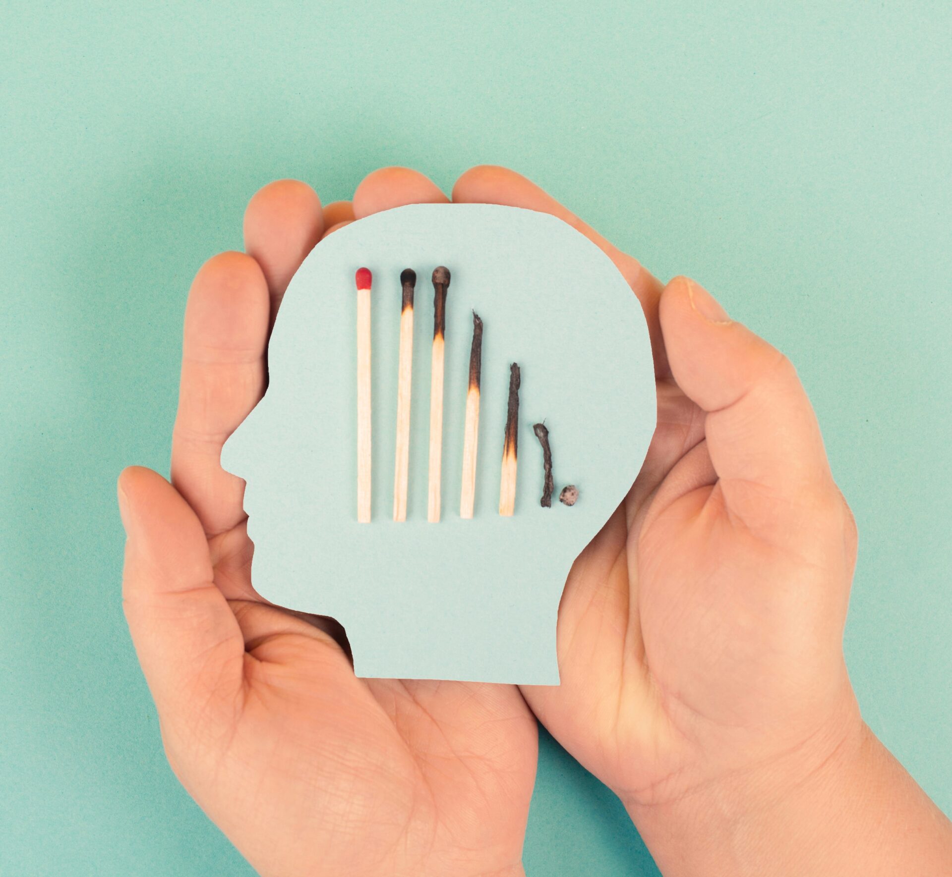 burnout symbolisiert durch unterschiedlich abgebrannte Streichhölzer auf einem Pappkopf.
